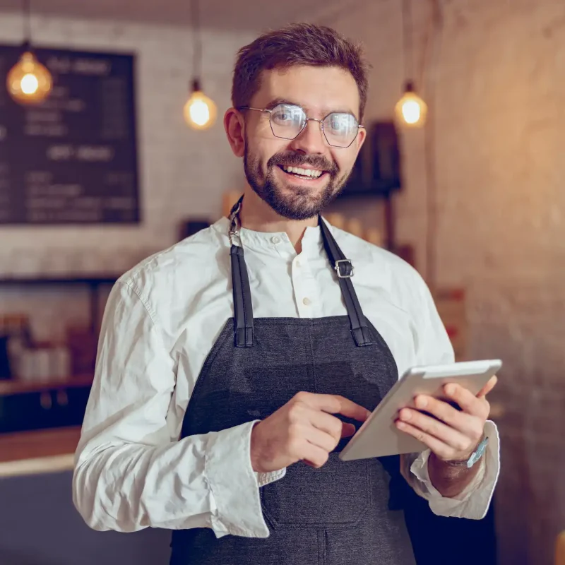 Joyful male worker using tablet computer in cafe
